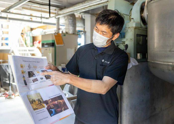 A soy sauce brewer guiding guests around a soy sauce brewery in Shiga.